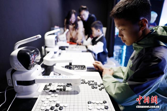 Một em nhỏ chơi cờ vây với robot.Ảnh: Ân Lập Cần - Phóng viên Chinanews