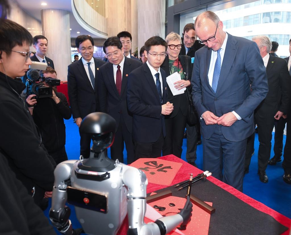 Ngày 26/2, Thủ tướng Đức Friedrich Merz xem robot hình người do công ty Unitree Robotics phát triển viết chữ "Phúc". (Ảnh: Tân Hoa xã)