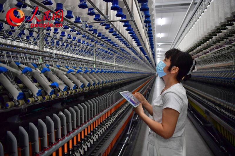 Công nhân kiểm tra máy móc tại một xưởng kéo sợi thông minh của Tập đoàn Dệt may Vệ Miên Giang Tây. Ảnh: Thời Vũ - Phóng viên Nhân Dân nhật báo điện tử