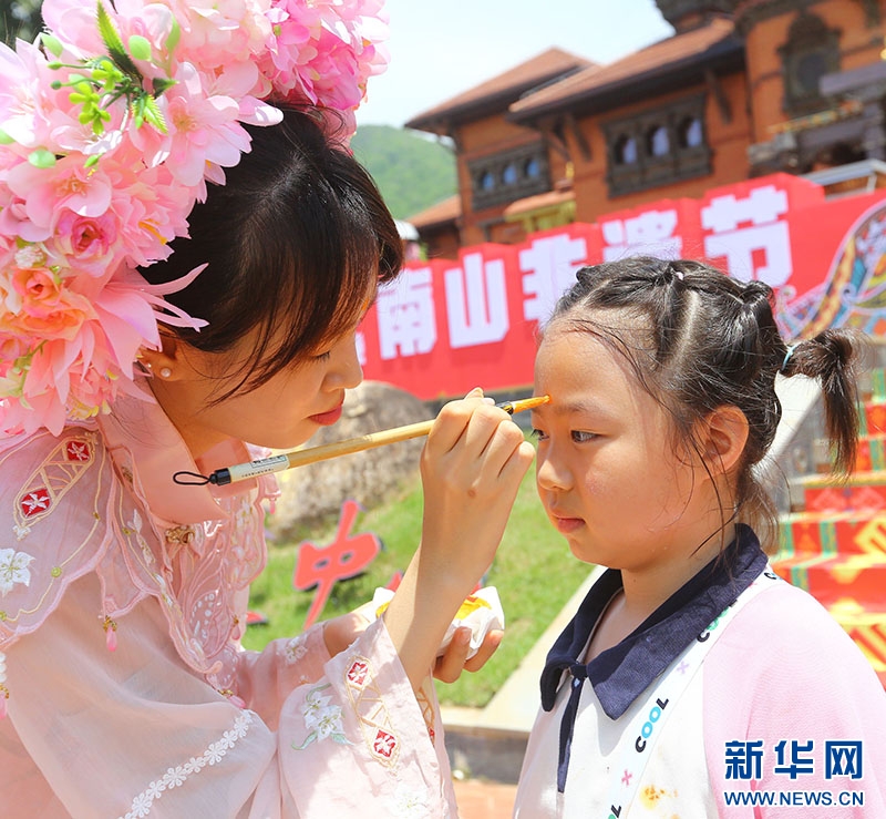 Phong tục dùng rượu hùng hoàng viết chữ “Vương” lên trán trẻ em. (Ảnh: Tân Hoa xã)