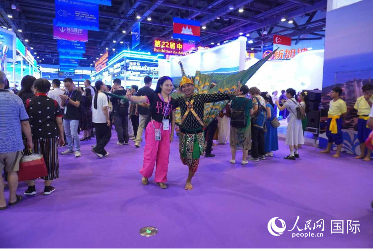 Du khách chụp ảnh lưu niệm cùng nghệ sĩ múa Campuchia tại khu triển lãm “Thành phố hấp dẫn” của Campuchia. Ảnh: Dương Xuân Yến – Nhân Dân nhật báo điện tử